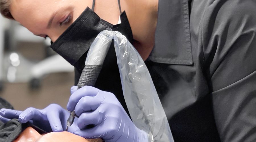 Woman applying permanent eyebrow makeup to a model