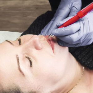 micropigmentation pen along top lip of female client. Lip blushing