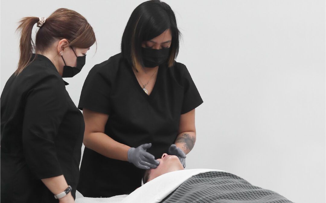 Esthetics student performing a facial under instructor supervision
