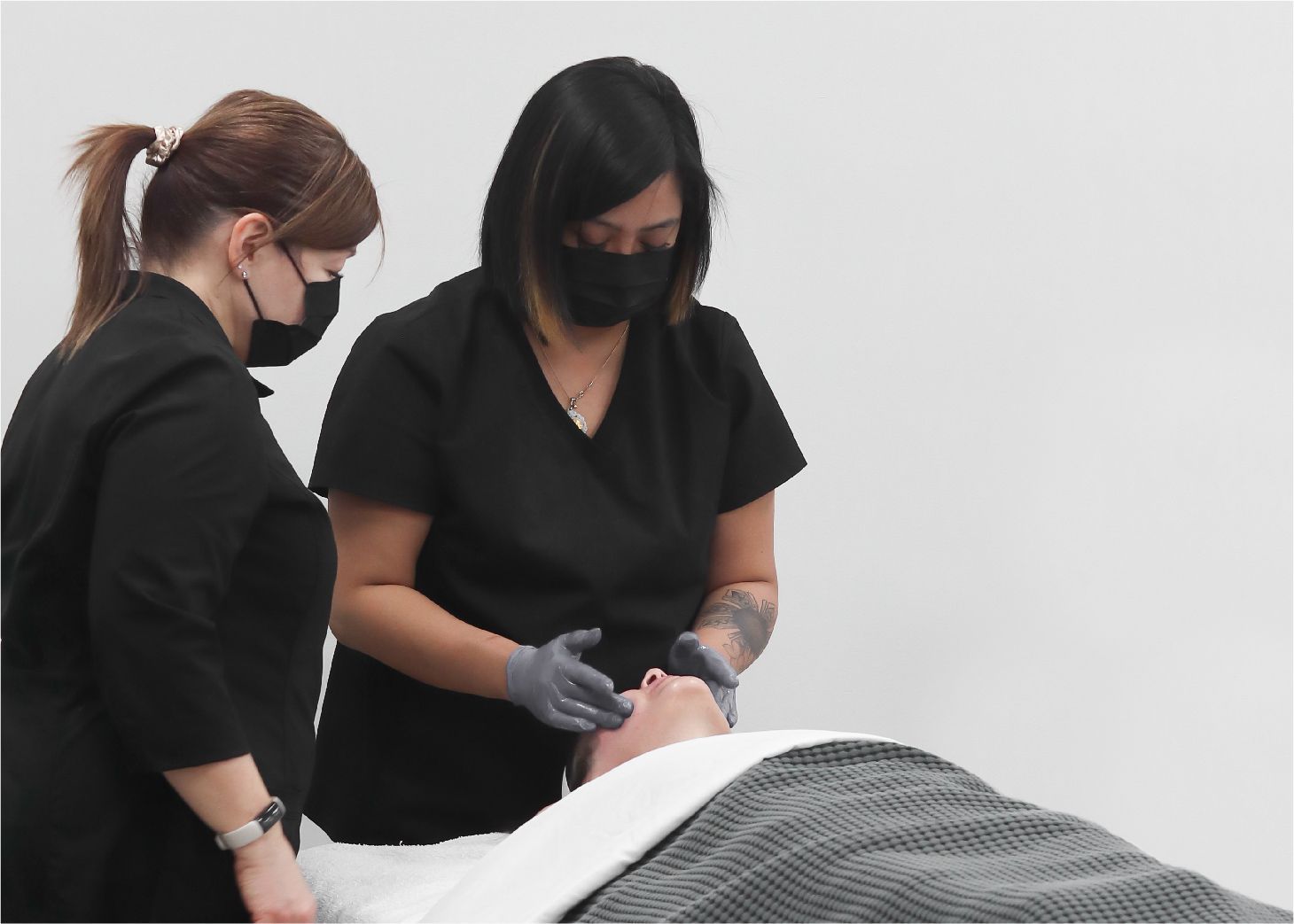 Esthetics student performing a facial under instructor supervision