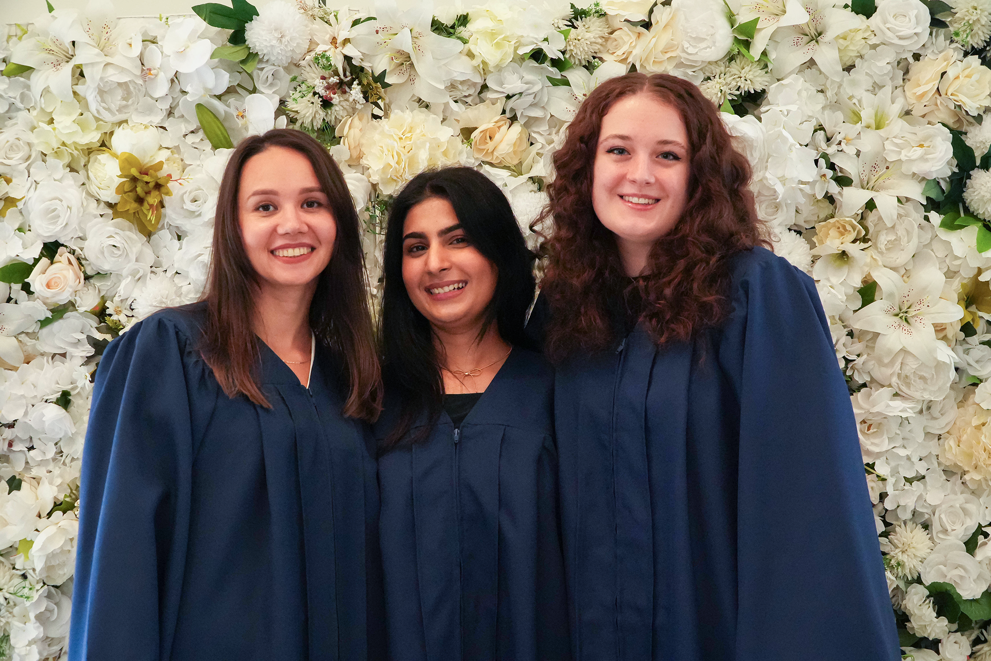 Wrapture Beauty Academy recent graduates in front of a flower wall. career college graduates Winnipeg