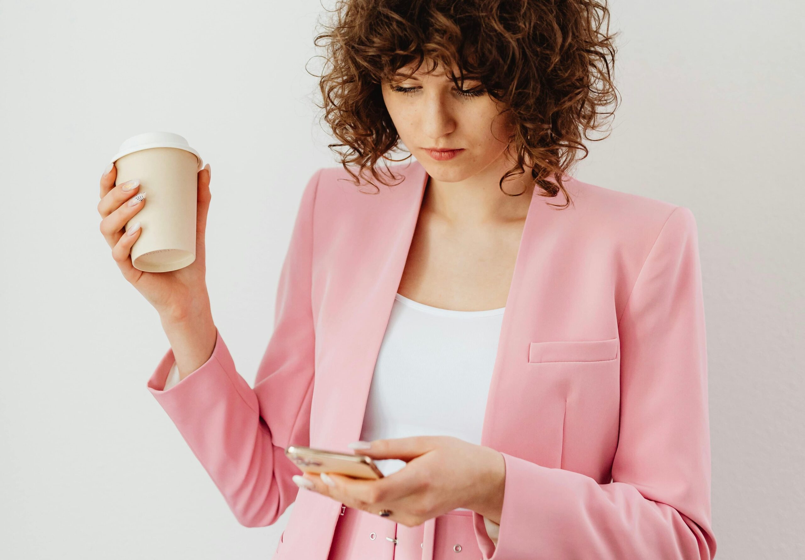 Esthetician in a pink suit working on branding during her coffee break