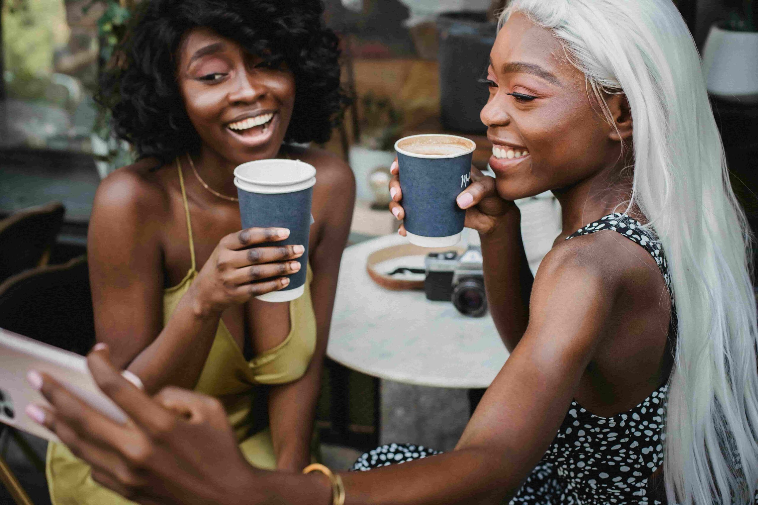 Two women enjoying coffee and taking a selfie, showing how everyday moments can be shared as authentic content in social media for estheticians.