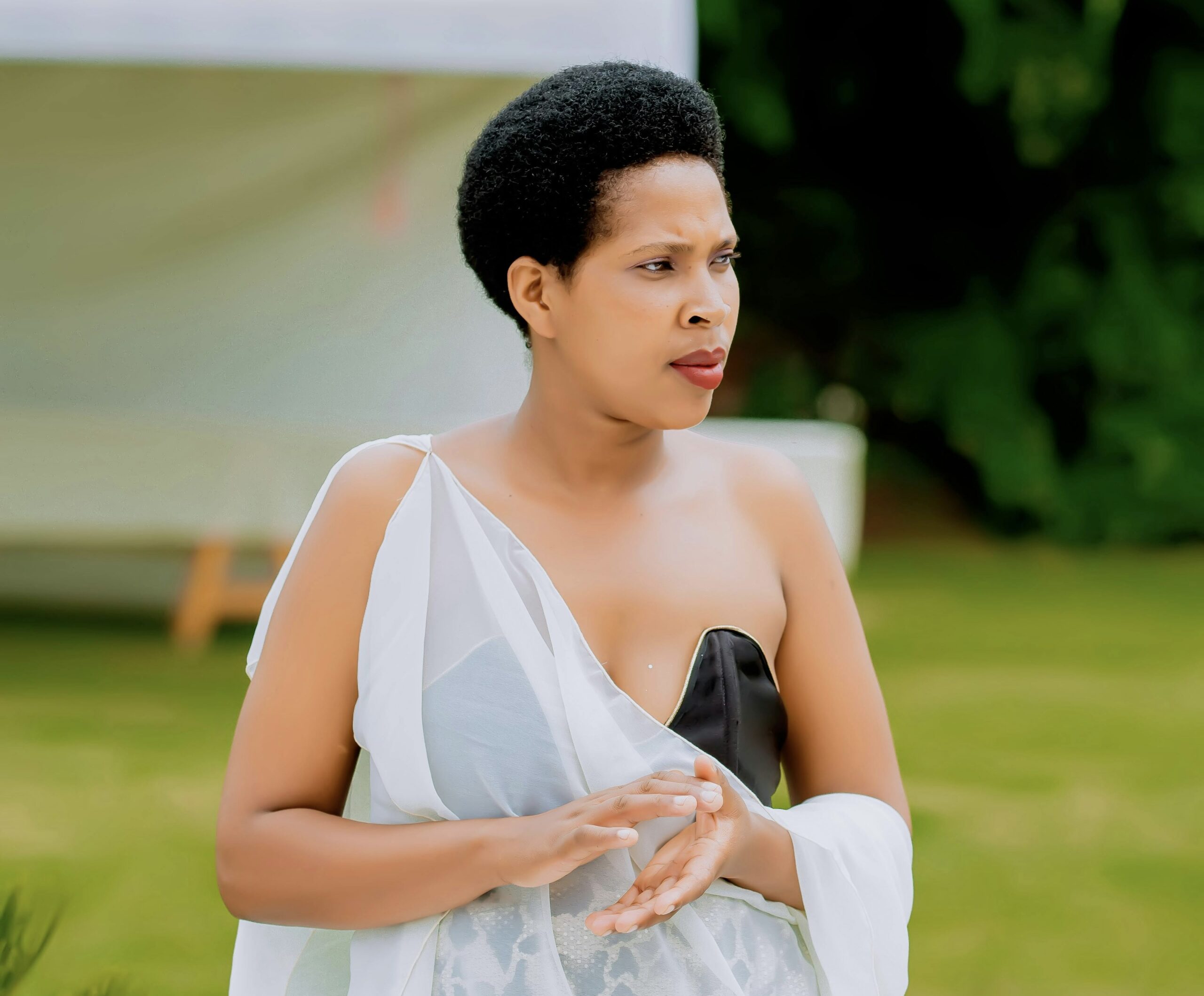 Elegant wedding guest in a flowing white dress outdoors, showcasing confidence and contour after RF body contouring treatment.<br />
