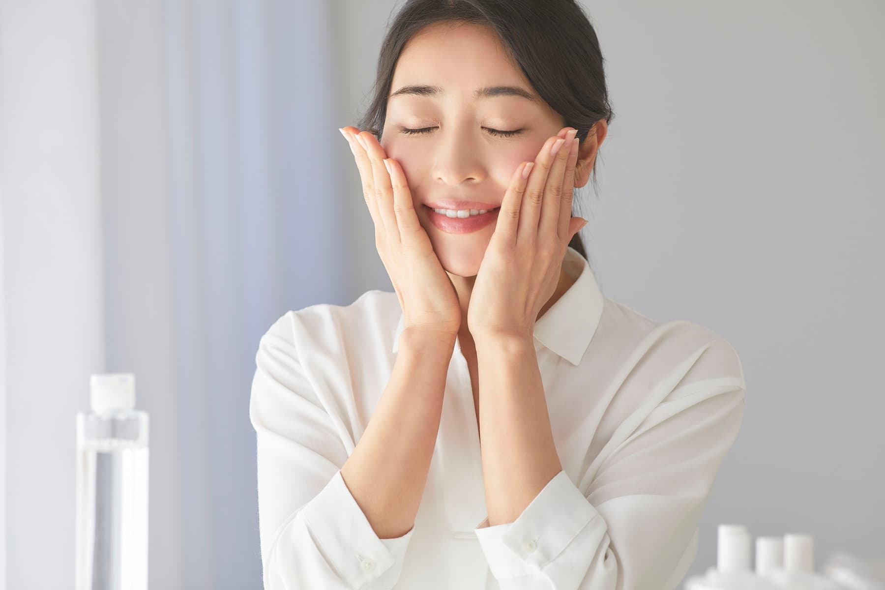 Woman gently applying skincare products to her face, demonstrating proper use of active skincare ingredients in an at-home routine.